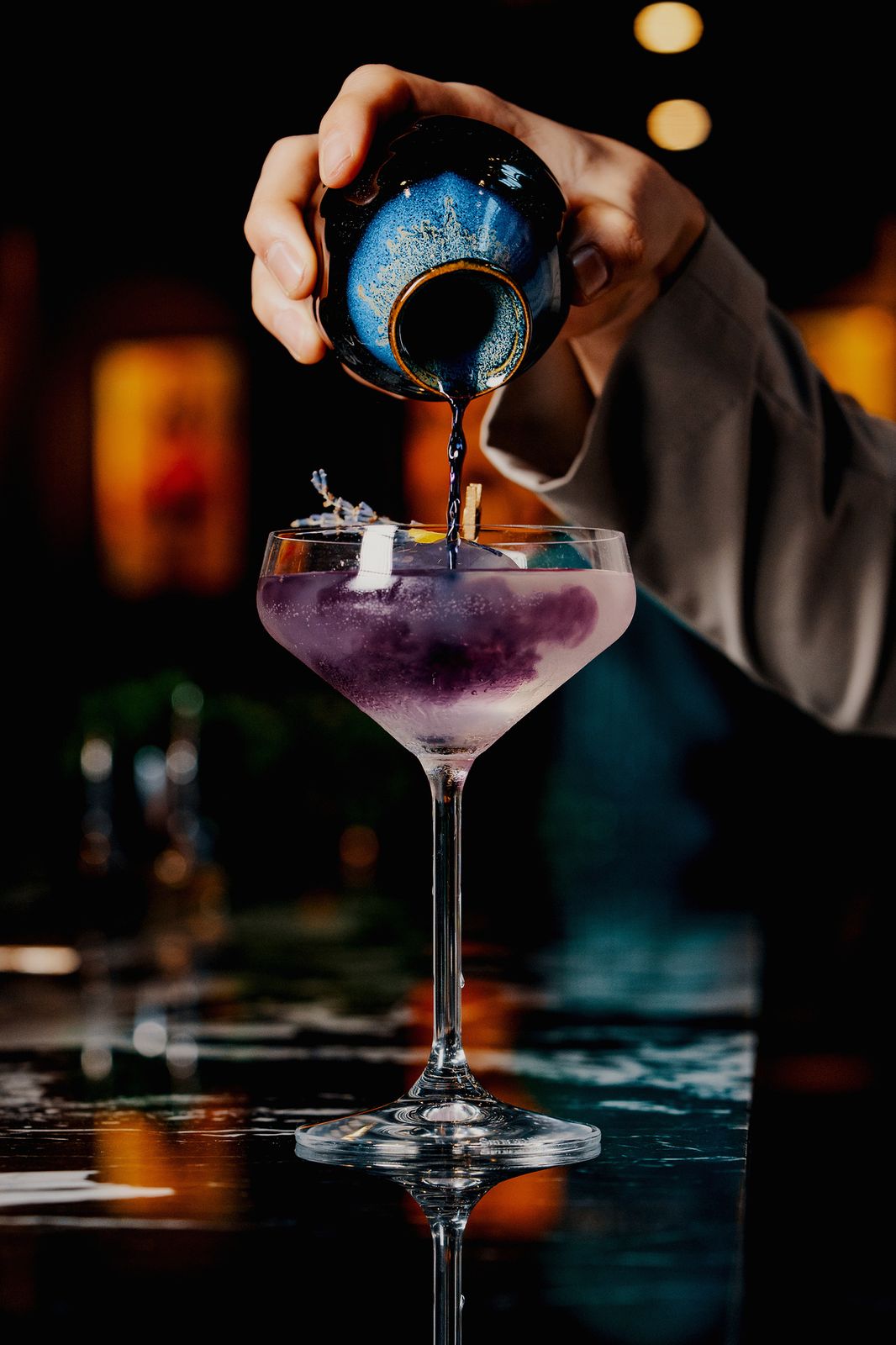 A violet cocktail being poured at the bar