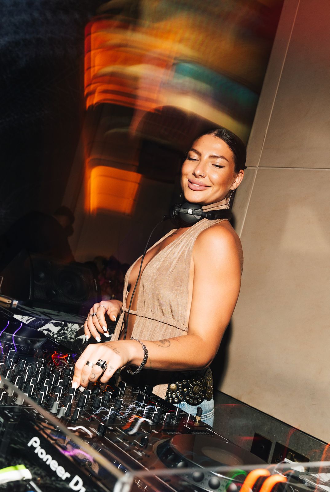 The DJ smiling behind the decks in violet light