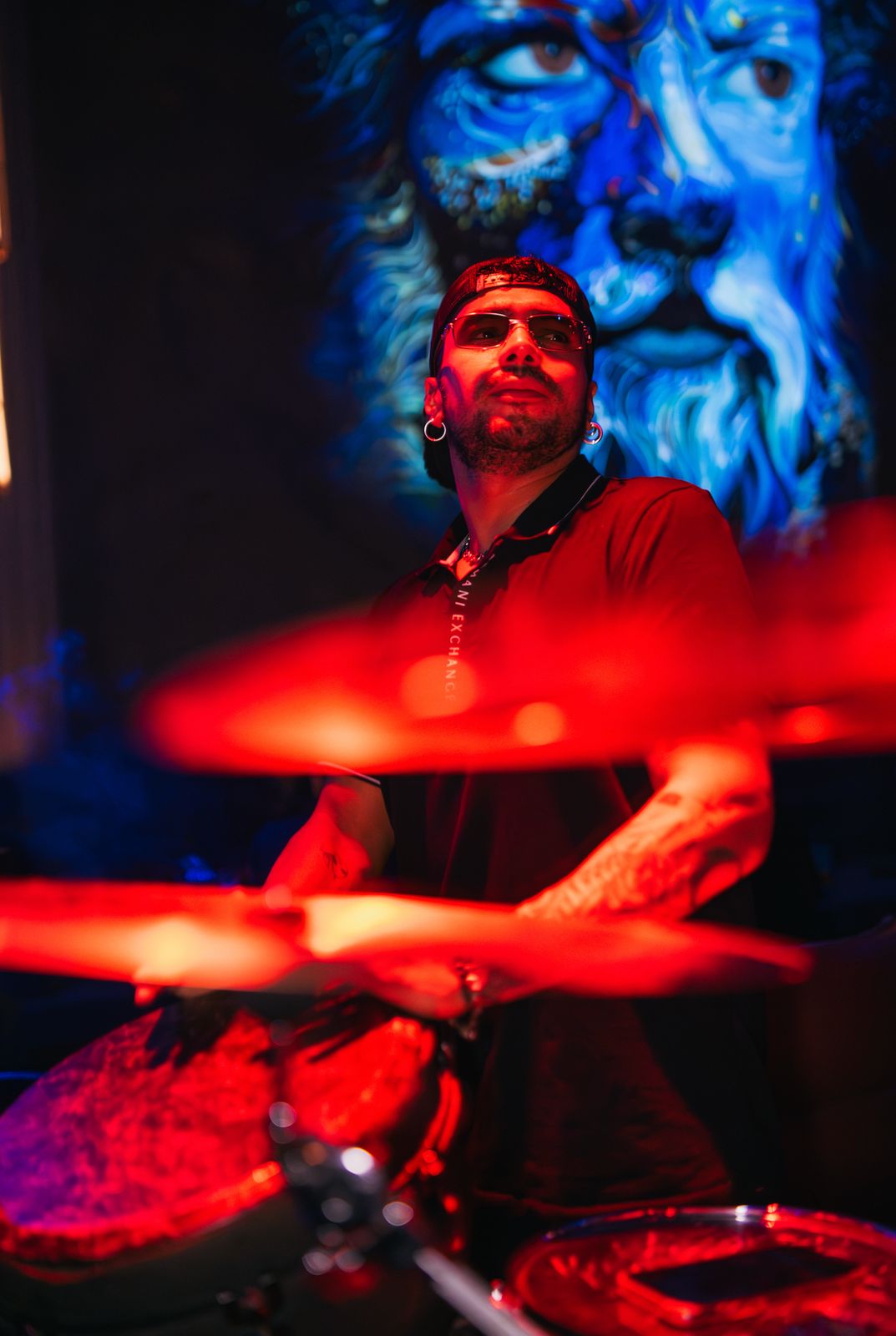 A live drummer mid-performance in red light