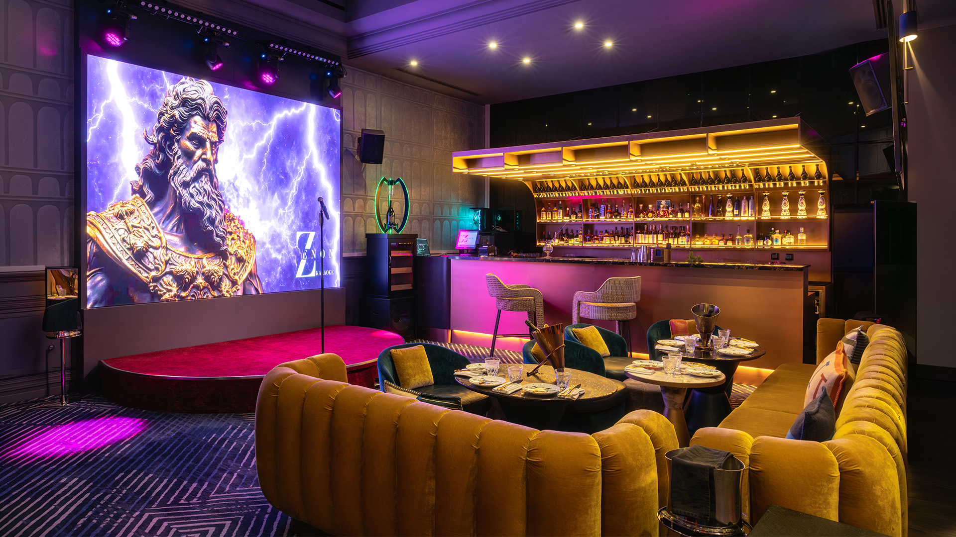 The karaoke hall: Zeus on the LED screen above the stage, the bar and velvet sofas